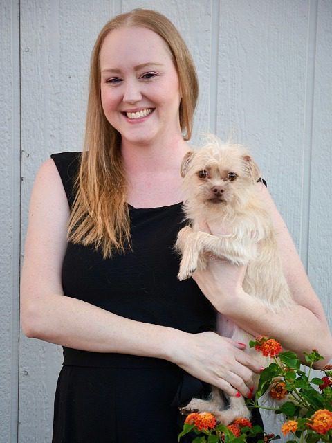 Coral -Female with blonde hair holding a small tan dog