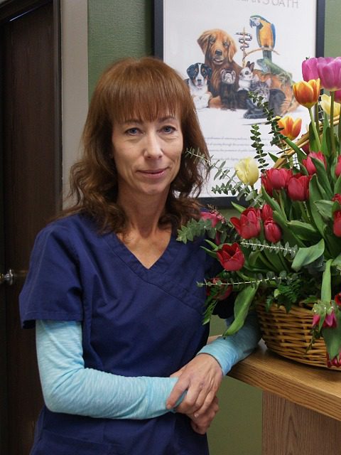 Monika - female wearing blue scrubs standing next to bouquet of flowers